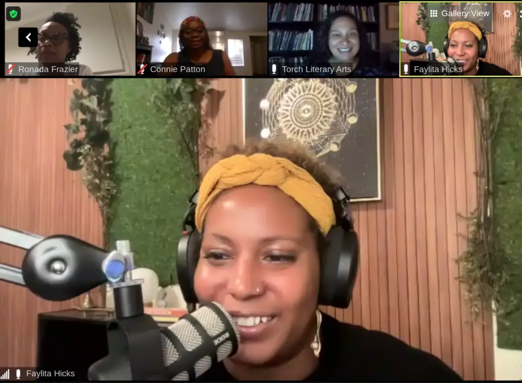 Screenshot of zoom meeting featuring five attendees. The largest image is of an Afro-Latin woman wearing a gold-colored headband. She is seated, wearing large black headphones and speaking into a microphone extending from the side of the screen.